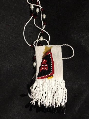 beaded Haida necklace featuring woman wearing yellow cedar hat and button blanket